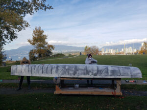 The hull of a robotic sailing vessel is being sanded by a person outdoors