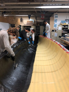 The hull of a robotic sailing vessel is being painted by a person indoors