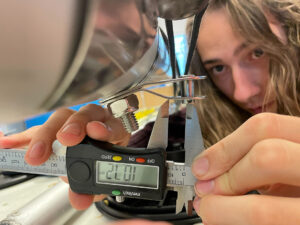 A close up of a man's face and his hands while he uses a tool to measure