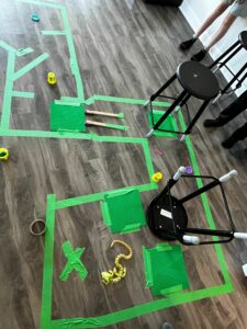 An outline is made on the floor of a classroom with green tape for a robotics exercise