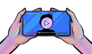 phone-playing-a-video_deciphering-deepfakes_rs_issue_10_deciphering_deepfake_2_web Hands holding a smartphone in landscape mode, displaying a video player interface. The screen shows the silhouette of a person with a large play button over their face, along with playback controls beneath the video